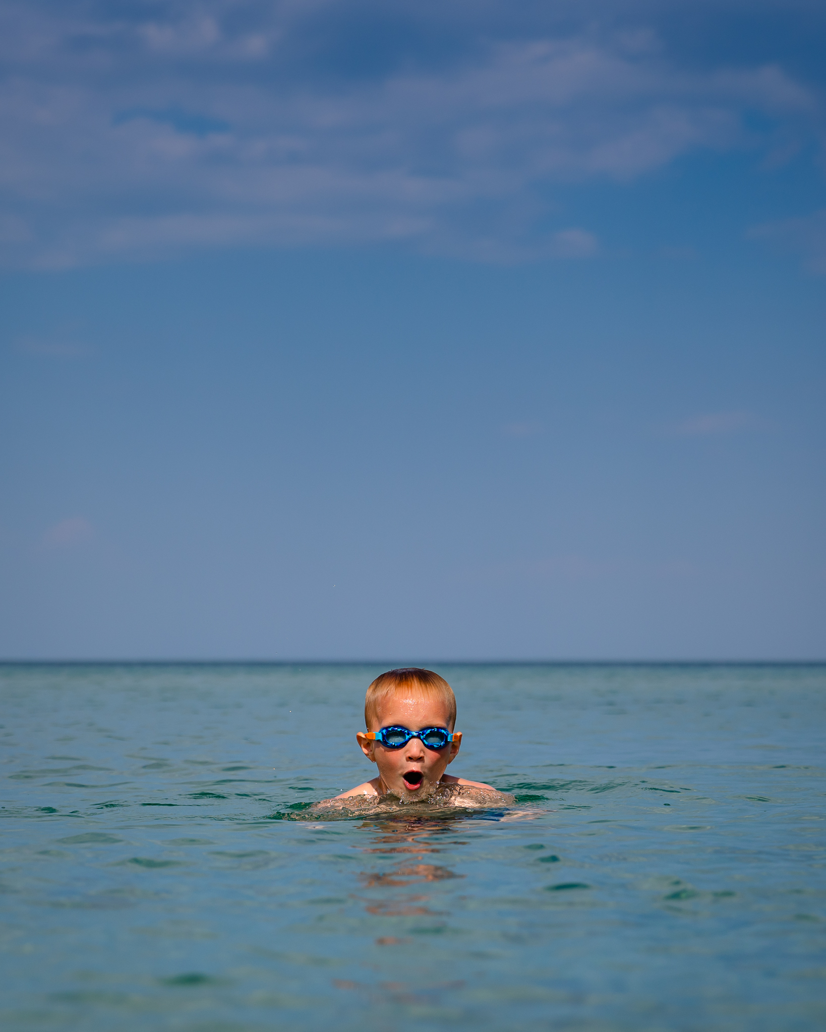 boy swimming in lake michigan wearing blue goggles